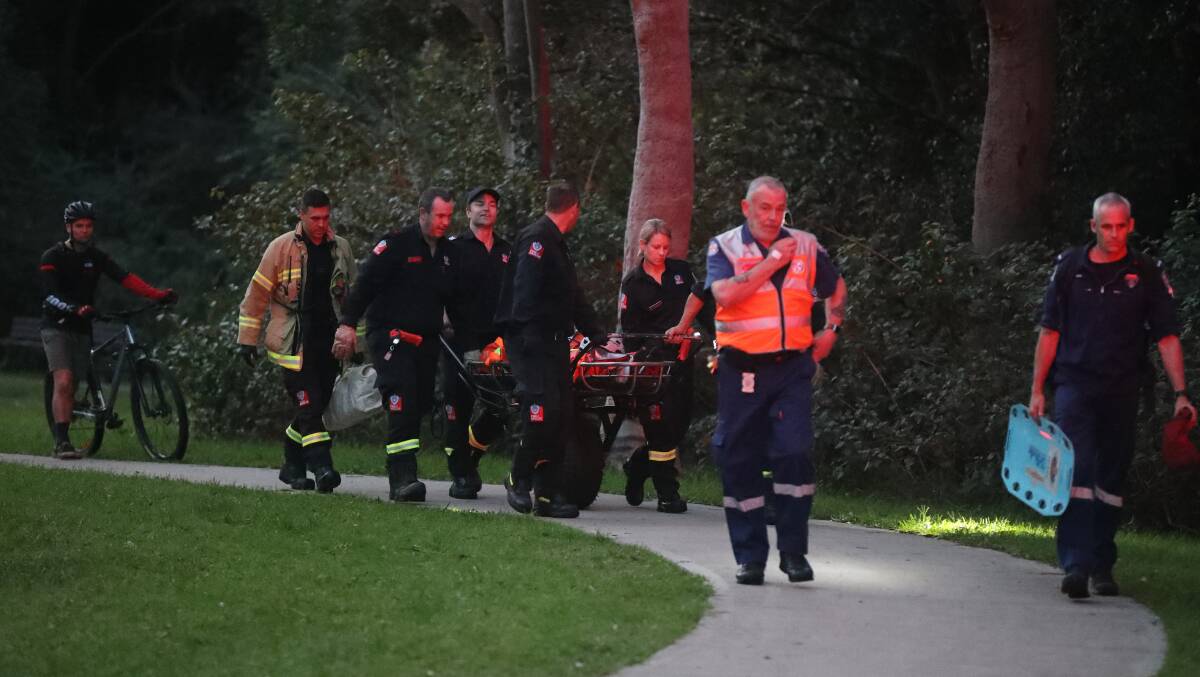 The injured rider and emergency services emerge from the bush at Balgownie Monday evening. Picture: Robert Peet 