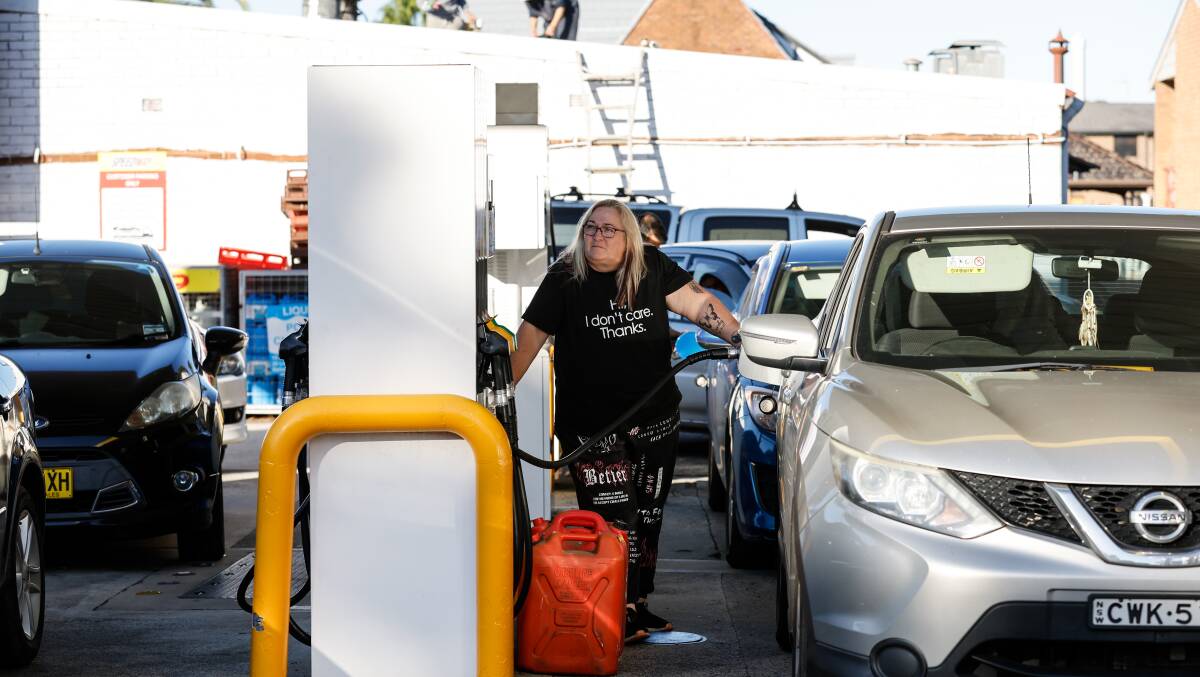 A woman refuels her car, and jerry cans, at the Speedway petrol station in Wollongong. Picture by Anna Warr