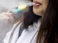 A file image of a woman smoking a disposable vape. 