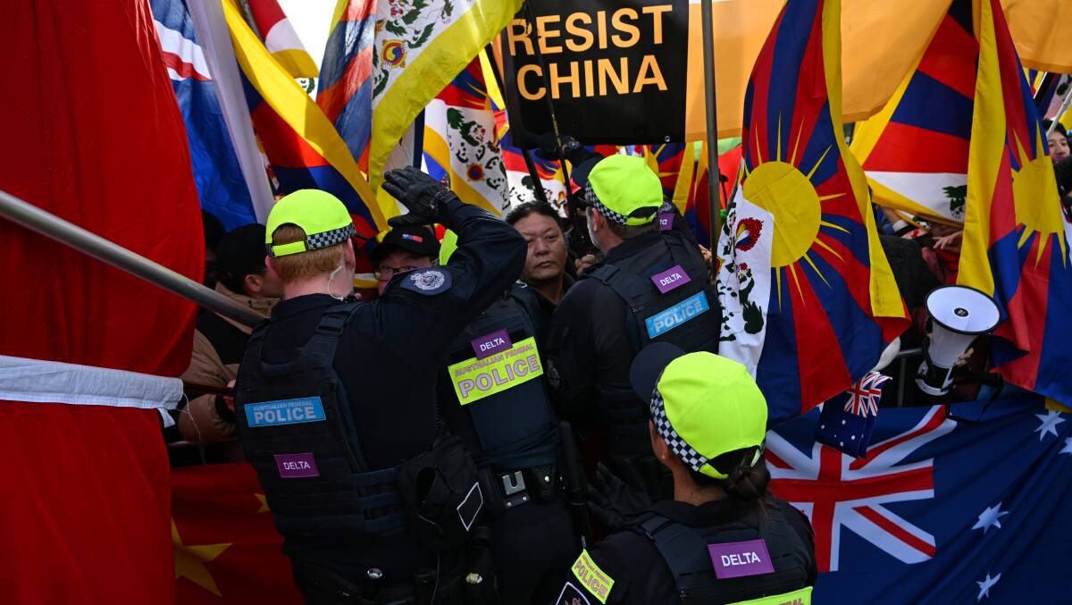 Police officers speak to protesters at a rally ahead of the visit by Chinese Premier Li Qiang to the Australian Parliament House in Canberra. Picture AAP