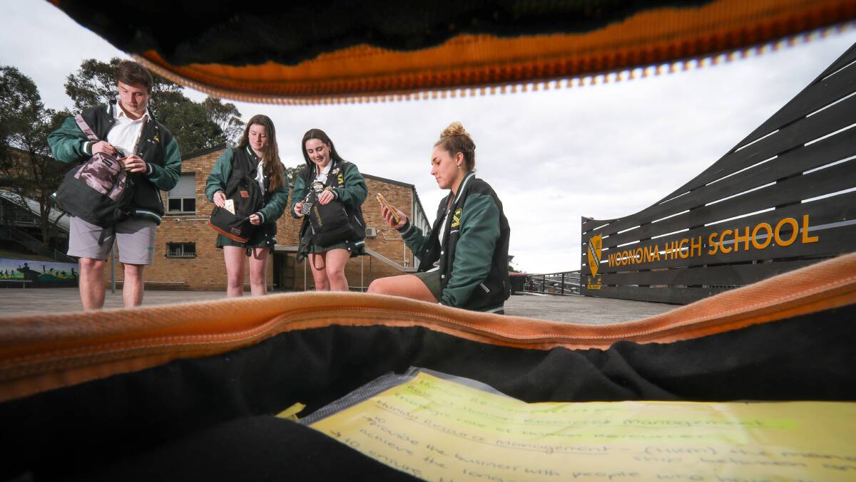 Woonona High School students (from left) Billy Sargent-Wilson, Madeleine Saxby, Finlay Smart and Summer Scarra check their phones after leaving school for the day. Picture: Adam McLean