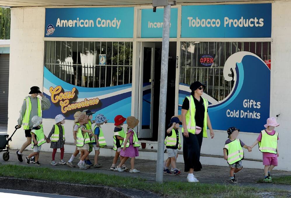 A group of preschoolers walks past the door of the candy and tobacco store which has popped up in Bulli this term. Picture by Robert Peet