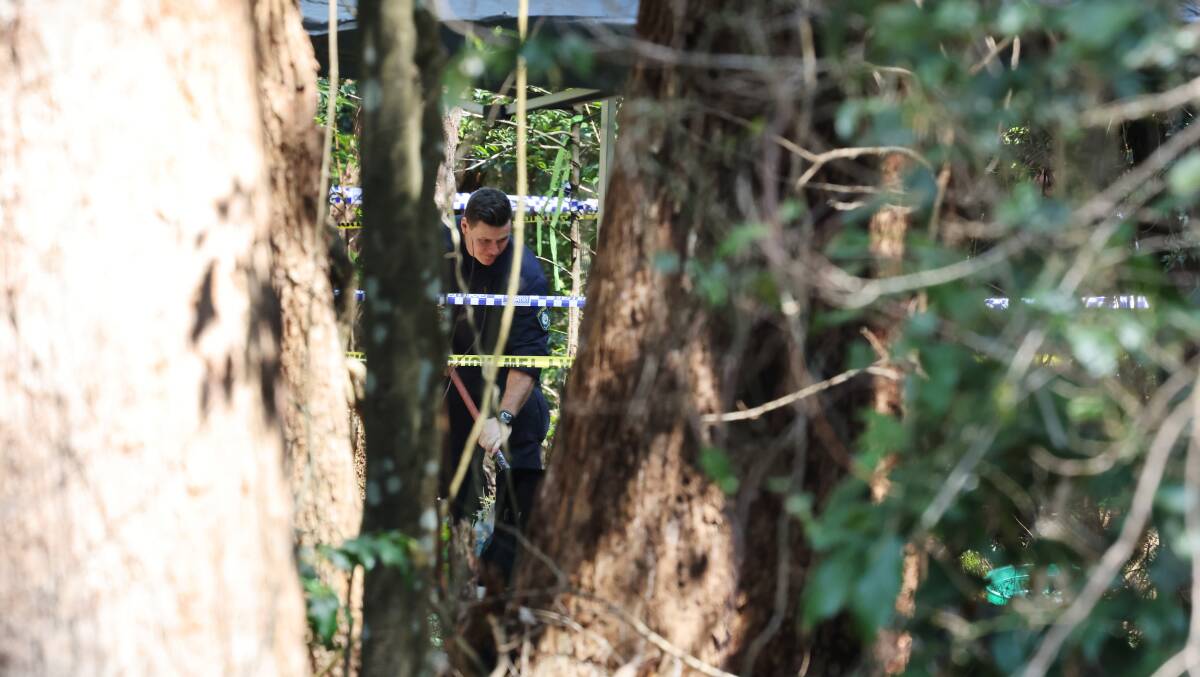 A police officer digs at the Mount Kembla site where human remains were found. Picture by Sylvia Liber