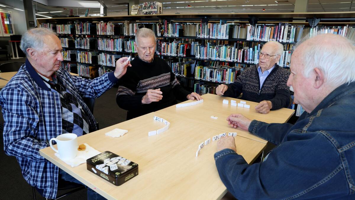 Old Boys Social Club members Joe Fernandes, left, Joao Coelho, Joe Palmearo and Ernest Mansell enjoy a game of dominoes at Warrawong Library. Picture by Sylvia Liber
