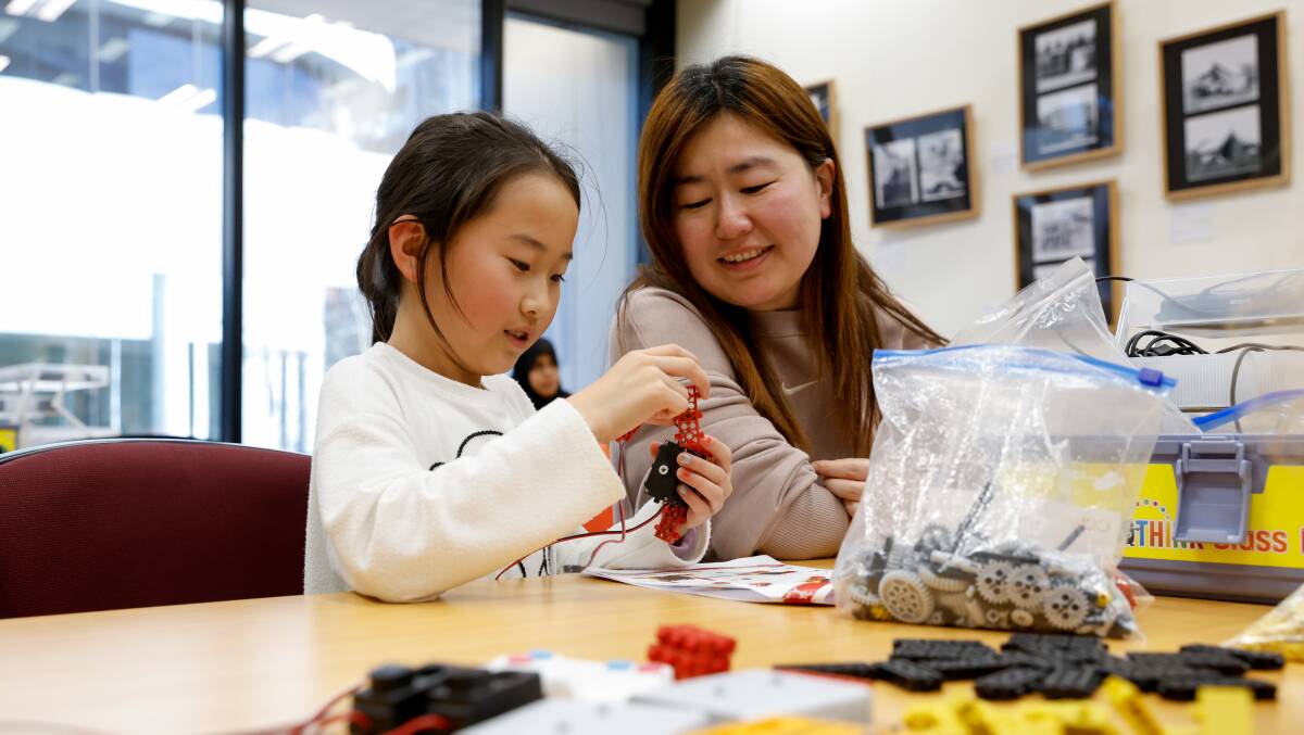 Caroline Wang, 8, enjoys a robotics workshop at Wollongong Library with her mother Joyce Jiao. Picture by Anna Warr