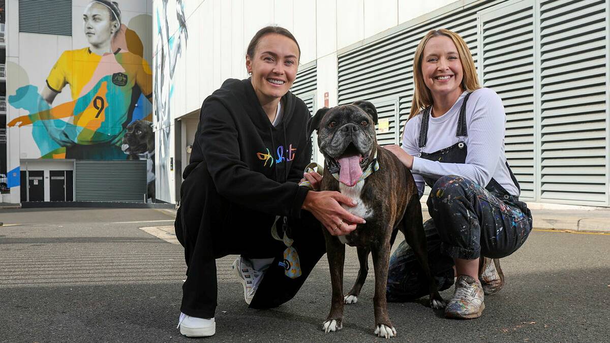 Caitlin Foord and her dog Peach with artist Claire Foxton, who painted a giant mural of Foord on the side of a Wollongong building. Picture by Adam McLean