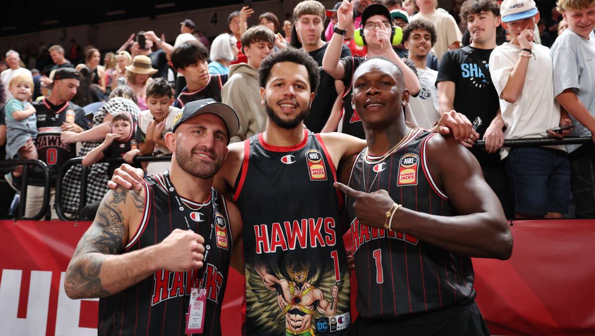 UFC stars Alex Volkanovski (left) and Israel Adesanya (right), pictured with Tyler Harvey, were on hand for the Hawks epic win over Brisbane on Saturday. Picture Getty Images