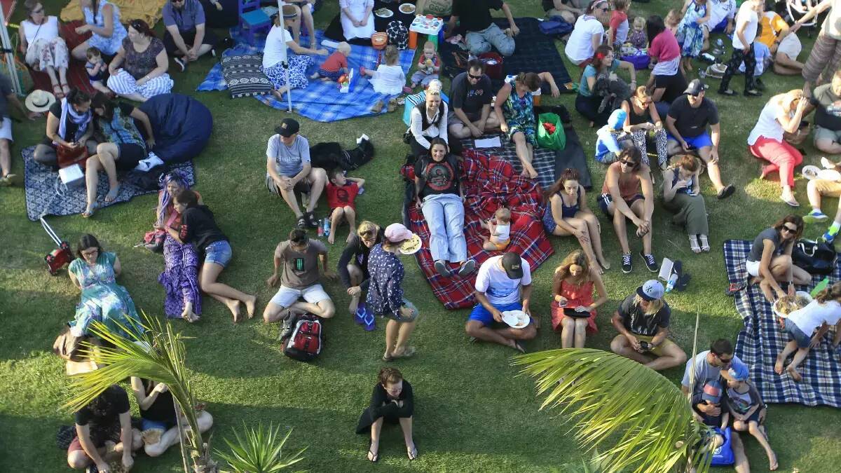 Marketgoers relax on the lawn at Bulli Showground. 
