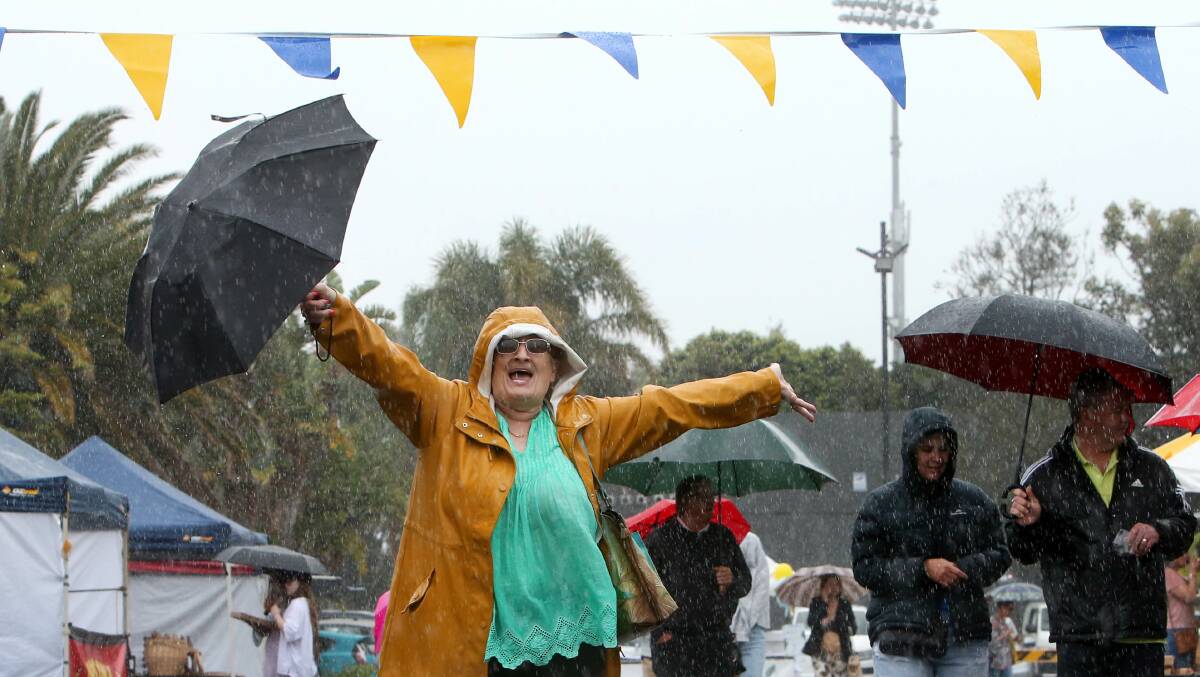 A file image of a woman standing in the rain at an outdoor festival. 
