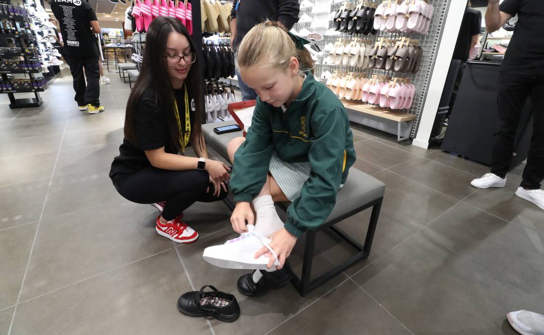 Warilla resident Mia Bailey, 8, trying on shoes with the help of JD Sports assistant Tayla Ristovska. Picture by Robert Peet
