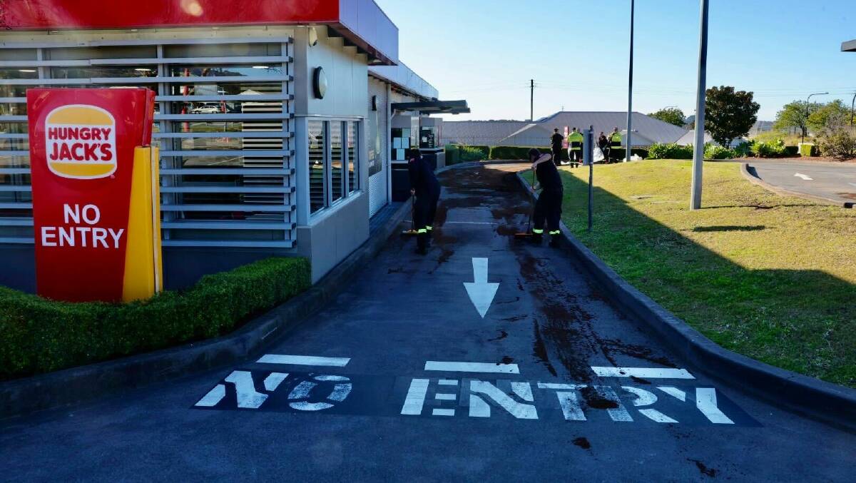 Firefighters putting down absorbent material on a fuel spill through the Hungry Jacks drive thru at Haywards Bay on Friday, June 28, 2024. Picture by Sylvia Liber 