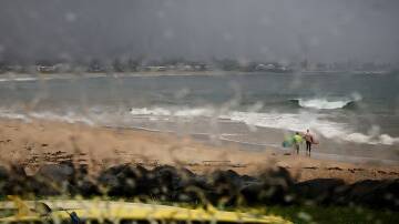 Two surfers brave the rain at Bellambi Beach on Sunday morning. Picture by Sylvia Liber